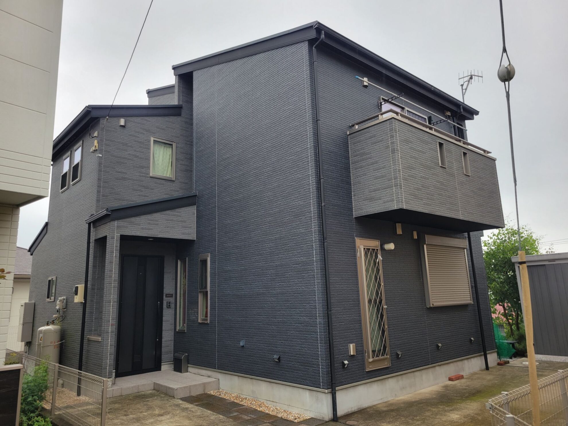 外壁塗装工事前の秦野市A様邸。黒系のサイディング外壁が特徴的な2階建て住宅