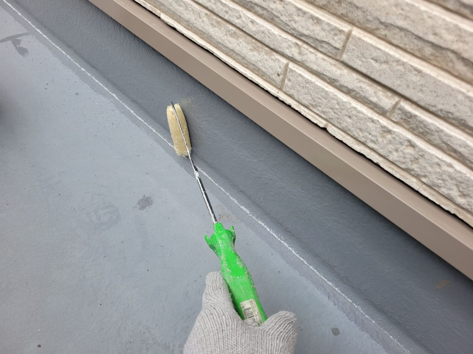 秦野市U様邸のFRPベランダでプライマーを均一に塗布している職人の作業風景