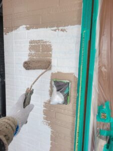 平塚市F様邸の玄関まわりで外壁の中塗りを進めている様子