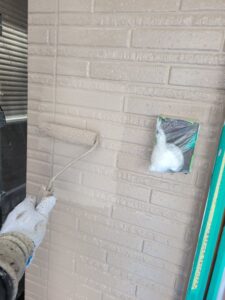 平塚市F様邸の玄関まわりで外壁の上塗りを行っている様子