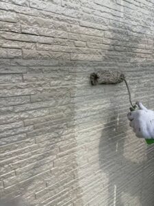 平塚市H様邸の外壁塗装で上塗りを進めている作業風景