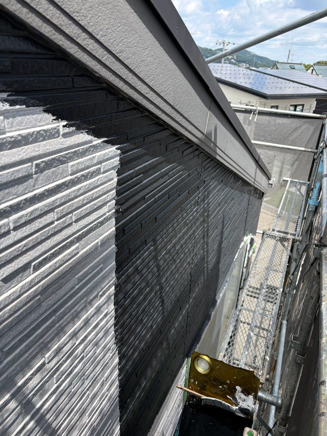 秦野市B様邸で外壁の中塗りを行い濃色の塗料を塗っている様子