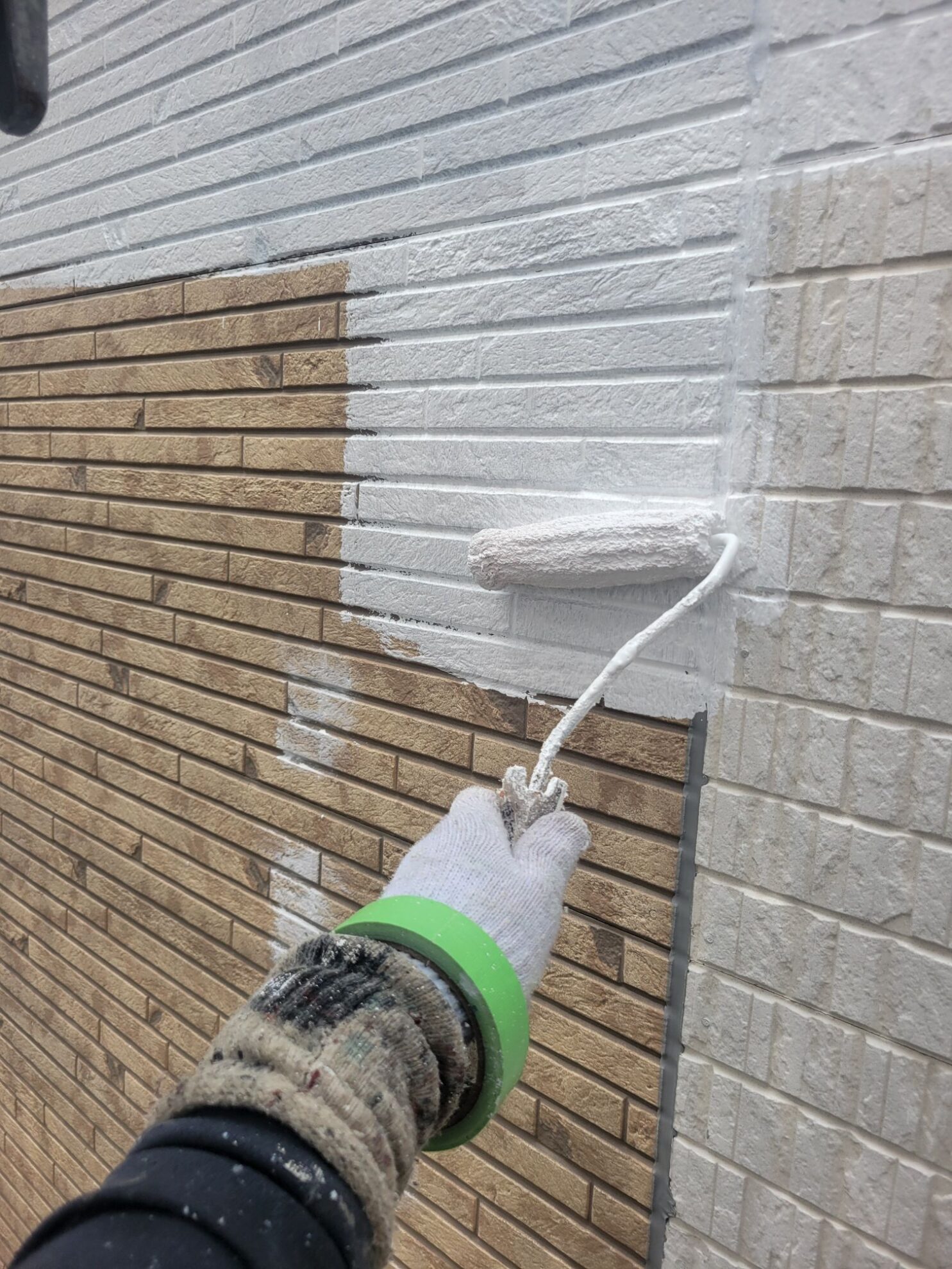 平塚市O様邸でサイディング外壁に下塗り材を塗布している様子