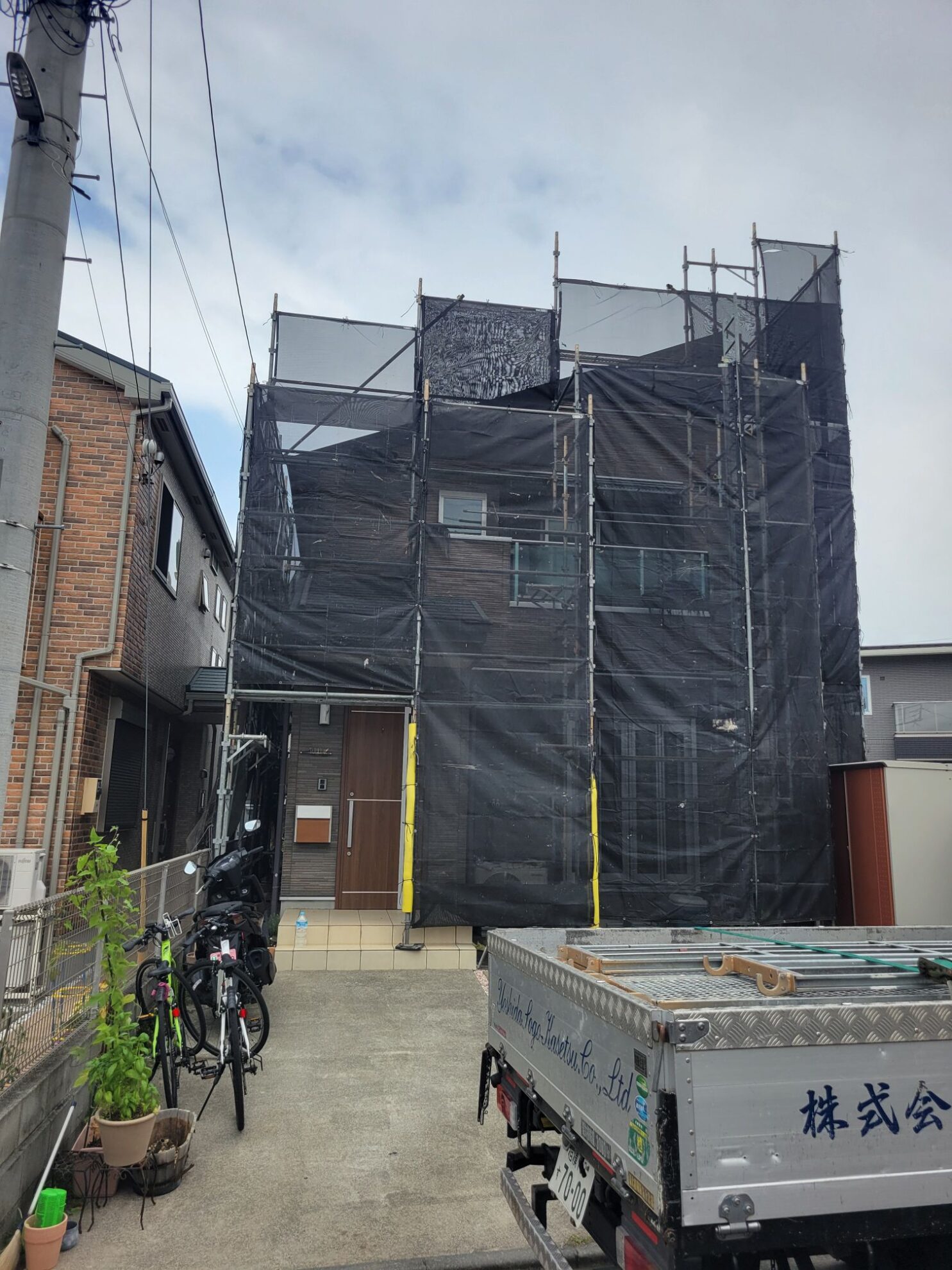 秦野市B様邸の玄関側に足場と飛散防止ネットを設置した様子