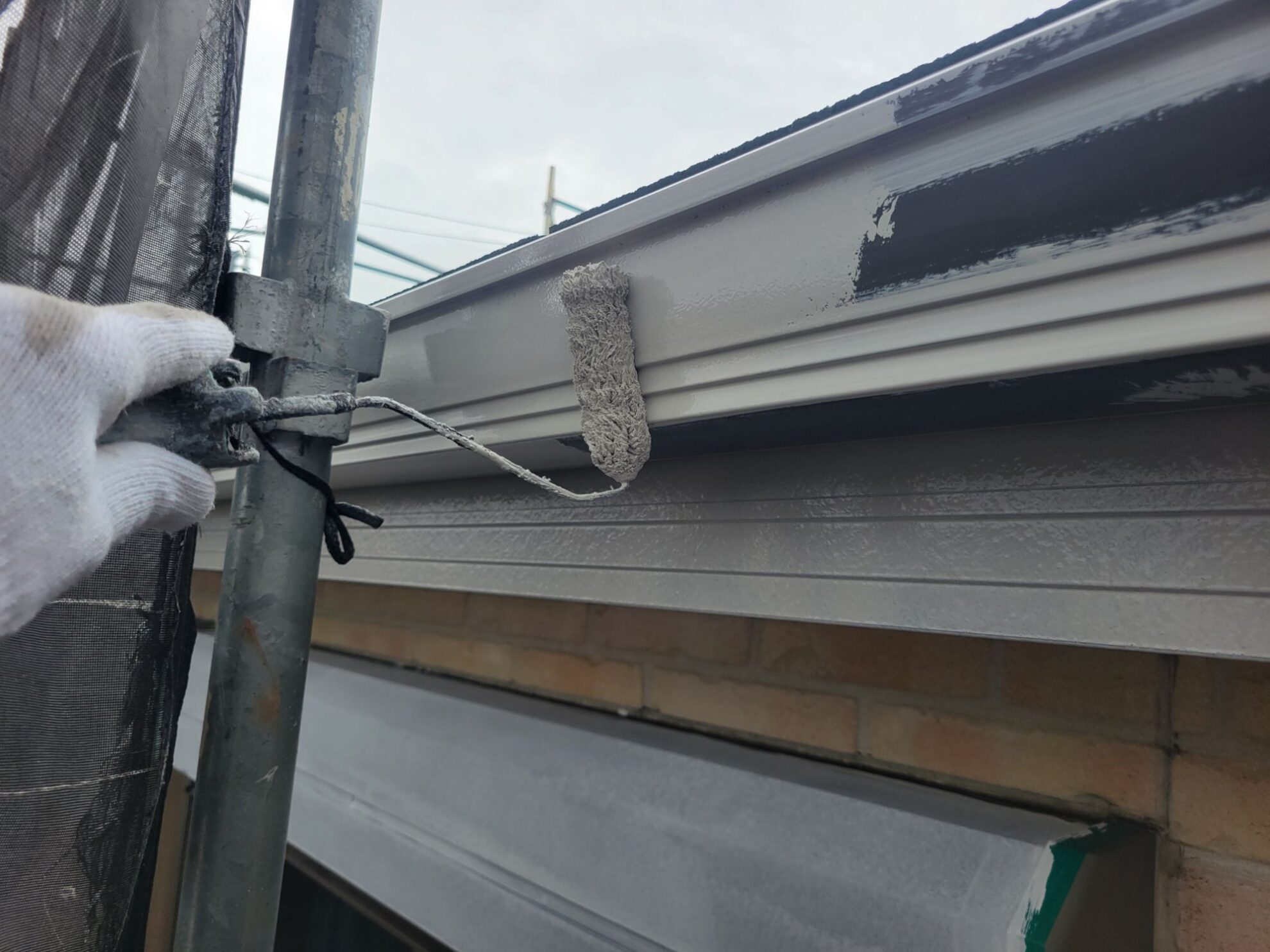 秦野市M様邸で雨樋を上塗りしている様子